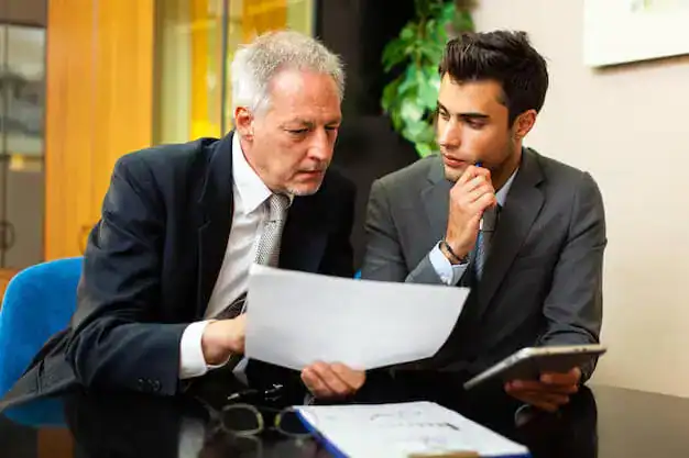 Two men discussing documents in office